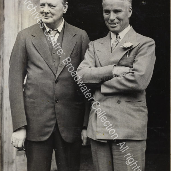 Photo shows WSC and Charlie Chaplain standing outside a doorway.