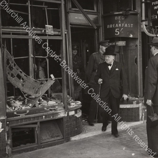 WSC is shown walking out of a bomb-damaged building. A sign behind him reads "Bed & Breakfast 5/".