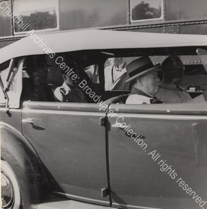 Photo of WSC and Franklin Roosevelt in the front of a vehicle. WSC has a cigar in his mouth and Roosevelt is driving
