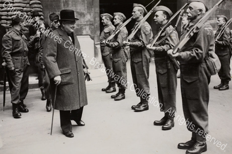 WSC inspects the Palace of Westminster Home Guard in Speaker's Court. Photo shows WSC wearing an overcoat and hat