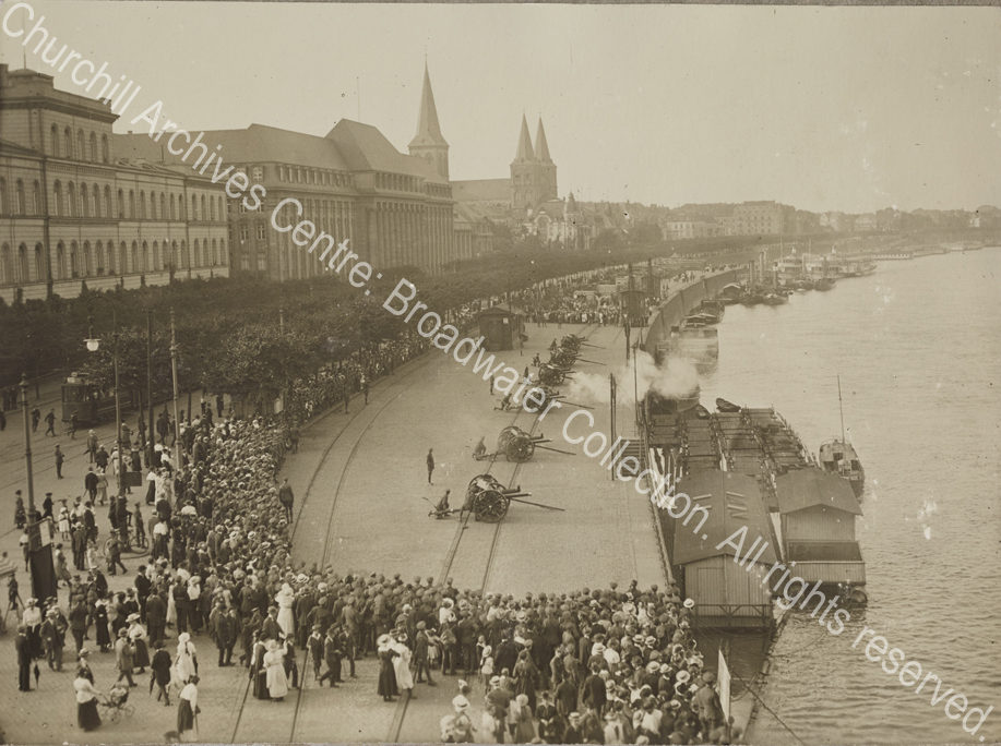 Photograph of field guns being fired on a city riverside [? Cologne