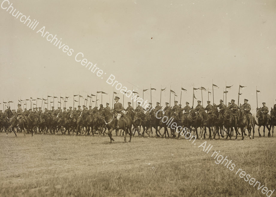 Photograph of a line of cavalry moving forward across open grassland [near Cologne