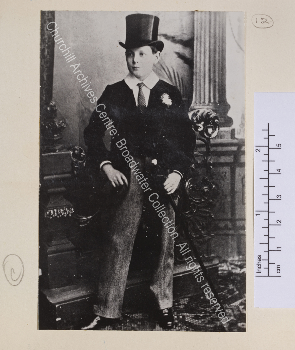 Portrait photograph of WSC as a schoolboy wearing a top hat and tailcoat and carrying a walking cane.