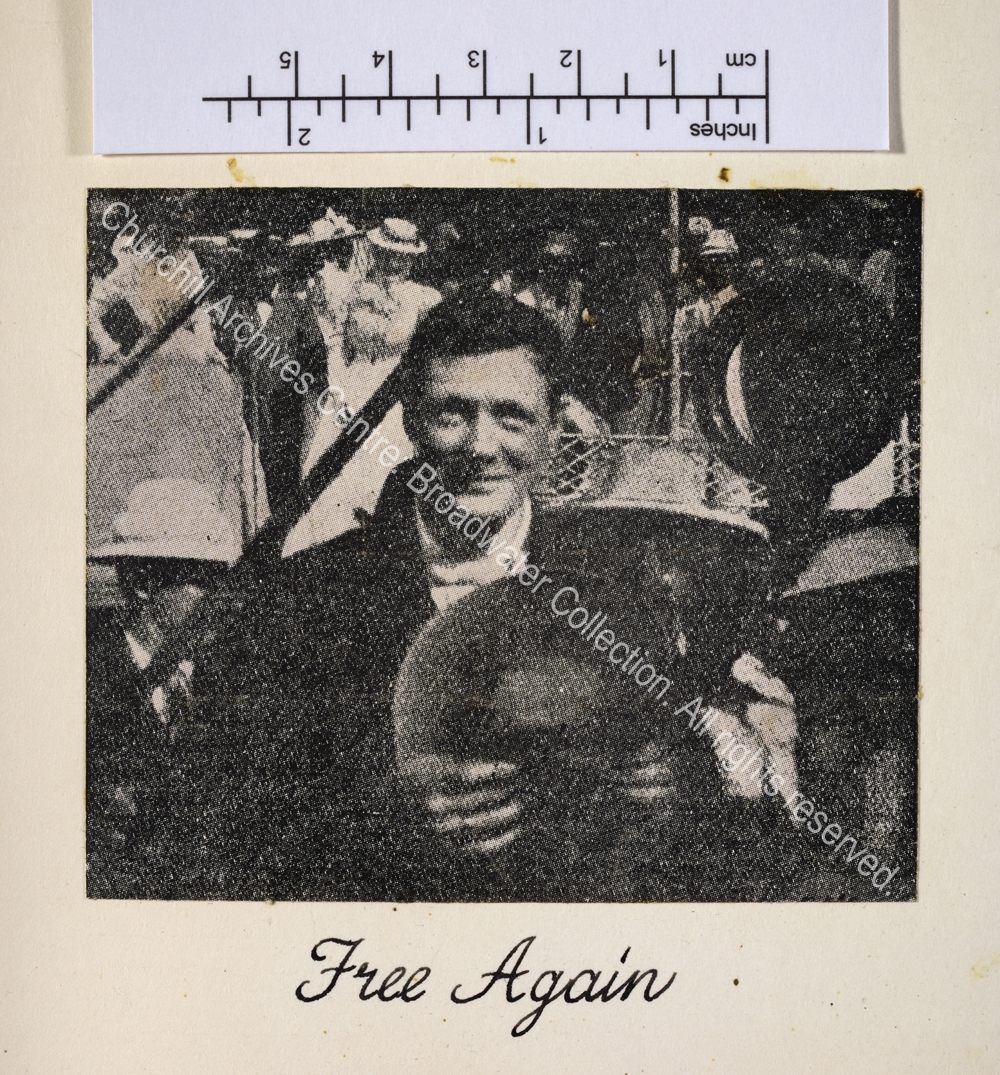 Image shows WSC (head and shoulders) in Durban smiling to camera holding his hat to his chest with a crowd of people and ship in the background.