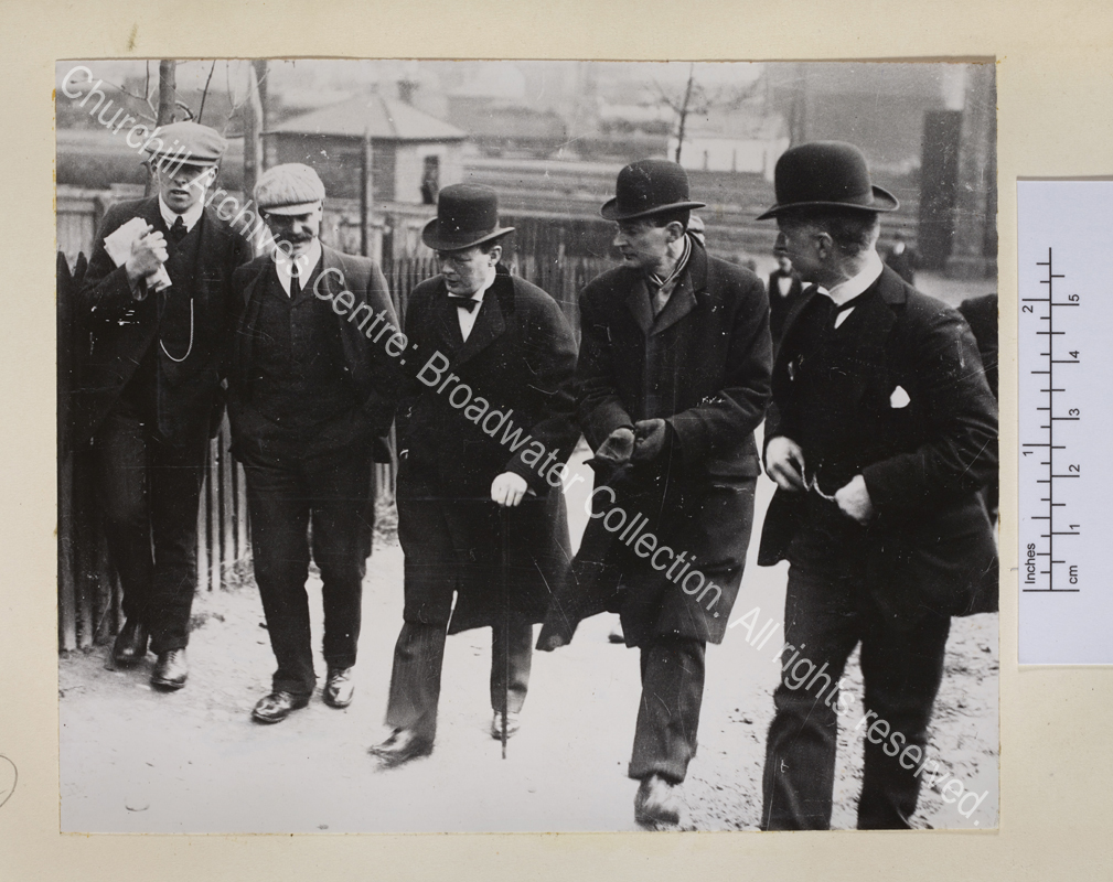 WSC walking along the street talking with a group of four men