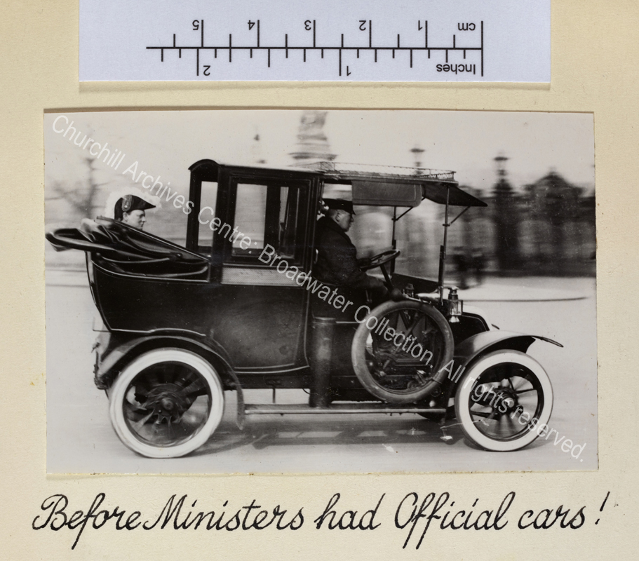Photo shows WSC in profile wearing Privy Councillor peaked feathered hat being driven in a car (?taxi) with folded hood.