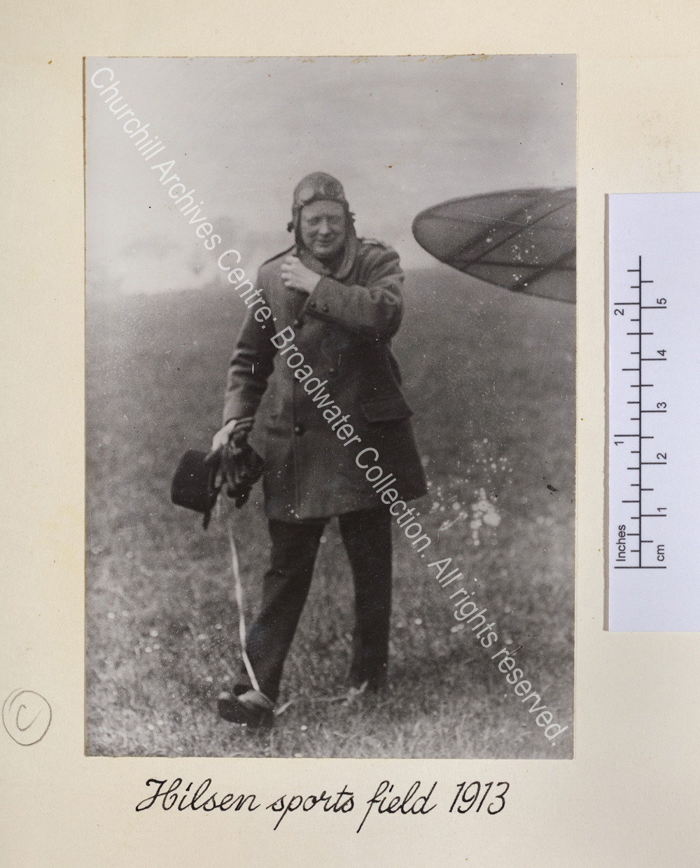 Photo shows WSC walking wearing a leather flying hat and goggles