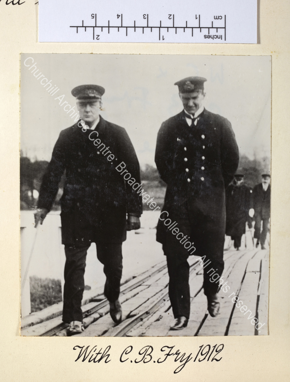 WSC wearing peaked cap and overcoat walking towards the camera with Charles Fry.