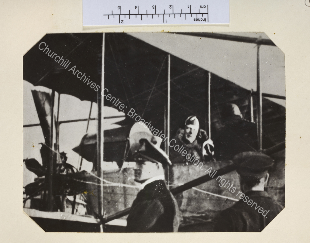 Photo shows WSC in the cockpit of a plane wearing leather flying hat.