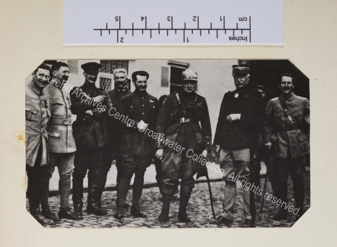 WSC in soldier's uniform and metal helmet in a group of people including (3rd from left) Captain Edward Spears and (to WSC's left) General Emile Fayolle.  Just seen behind the General is a German prisoner wearing a cap.