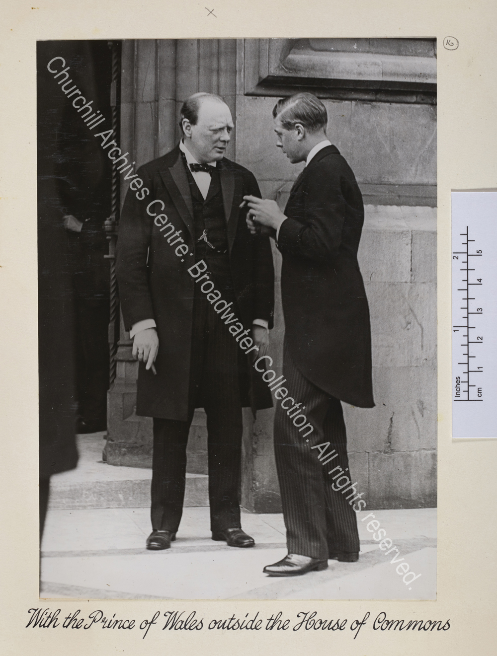 The Prince of Wales standing with WSC and listening to him. Both are holding cigars.