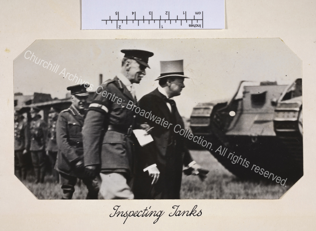Photo shows WSC wearing a top hat and carrying a walking cane looking intently at a tank during visit to inspect British forces in Cologne