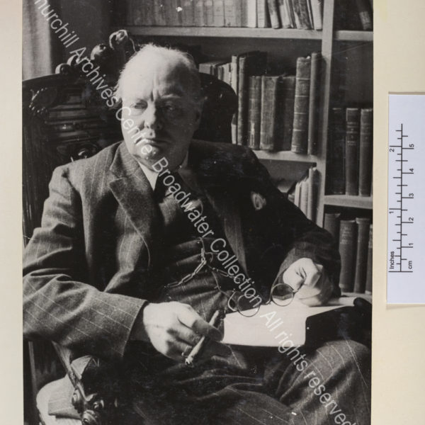 Photo shows WSC seated with a book on his lap