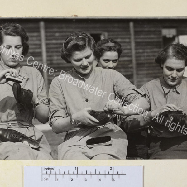 Photo shows Mary Churchill [later Mary Soames] with 3 other ATS [Auxiliary Territorial Services] recruits seated on the grass polishing lace up shoes.