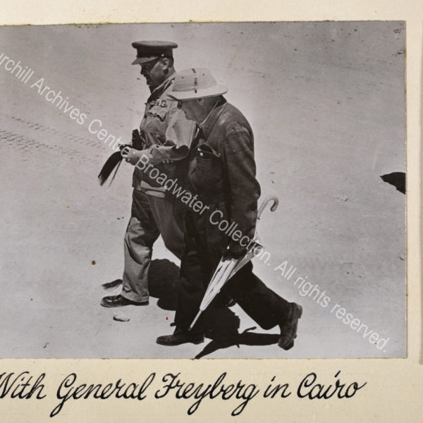 Photo shows WSC wearing a pith helmet walking with Lieutenant General Sir Bernard Freyberg [Commander 2nd New Zealand Division