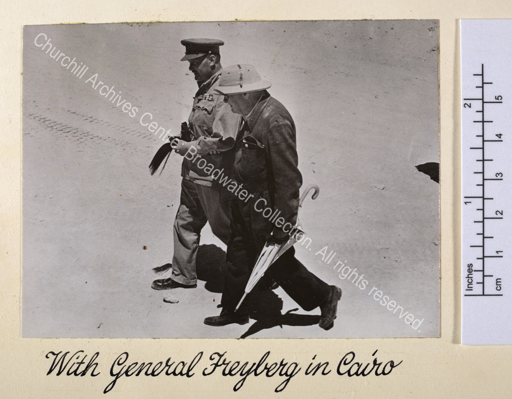 Photo shows WSC wearing a pith helmet walking with Lieutenant General Sir Bernard Freyberg [Commander 2nd New Zealand Division