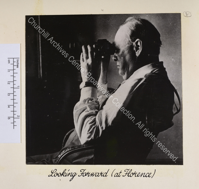 Photo of WSC in profile seated and looking through a pair of binoculars