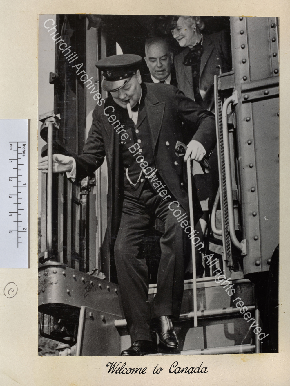 Photo shows WSC climbing down from his train arriving for the second Quebec Conference. He is wearing a peaked cap and has a cigar in his mouth. Behind him are CSC and Mackenzie King [Prime Minister of Canada]