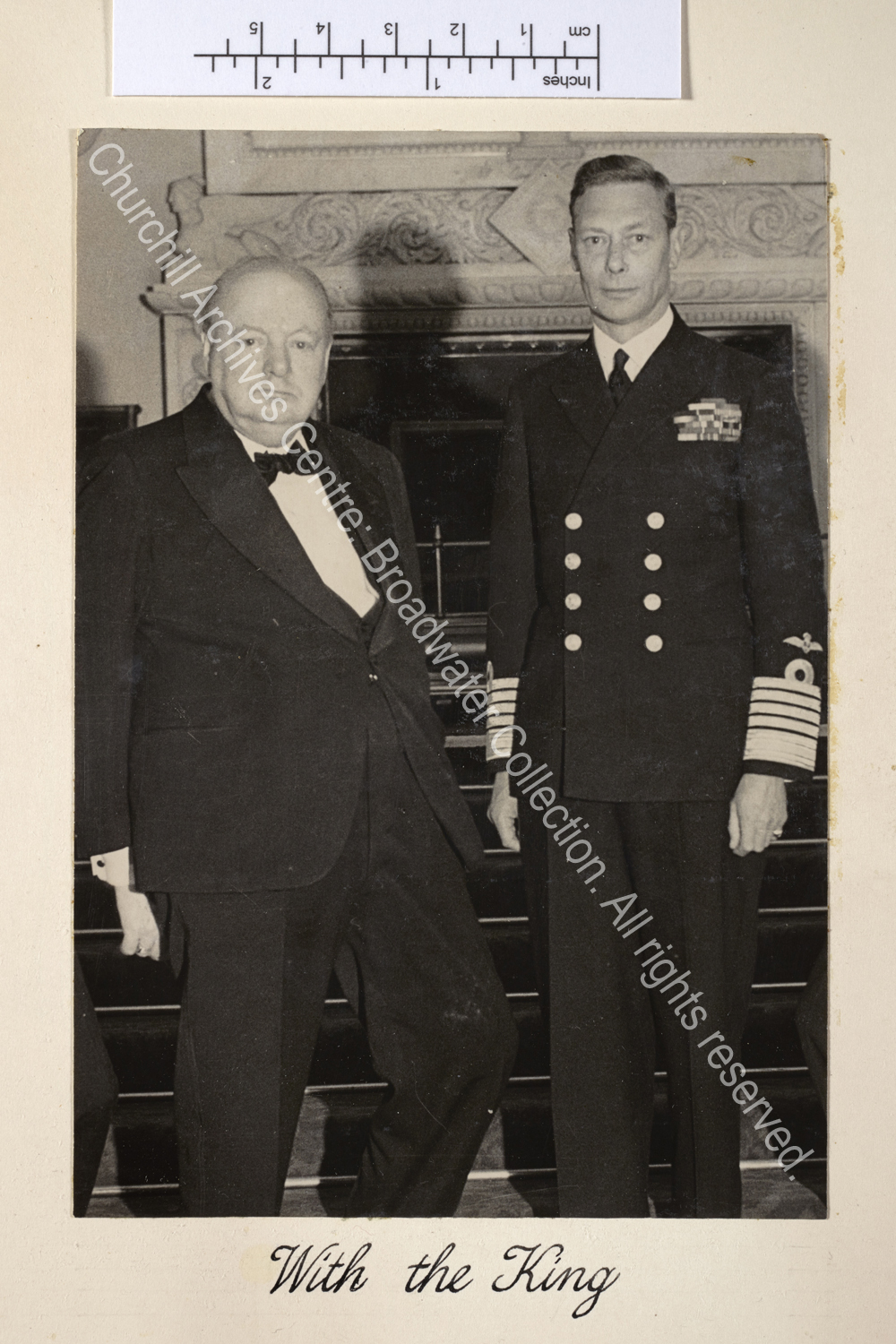Photo shows WSC standing next to King George VI. The King is in uniform and WSC is wearing a dinner jacket and black tie.