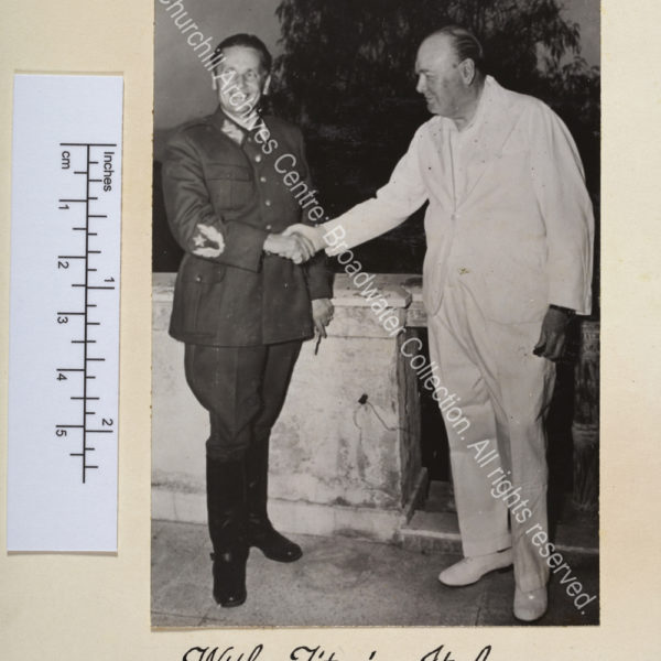 Photo shows WSC wearing a white suit shaking hand with Marshal Tito