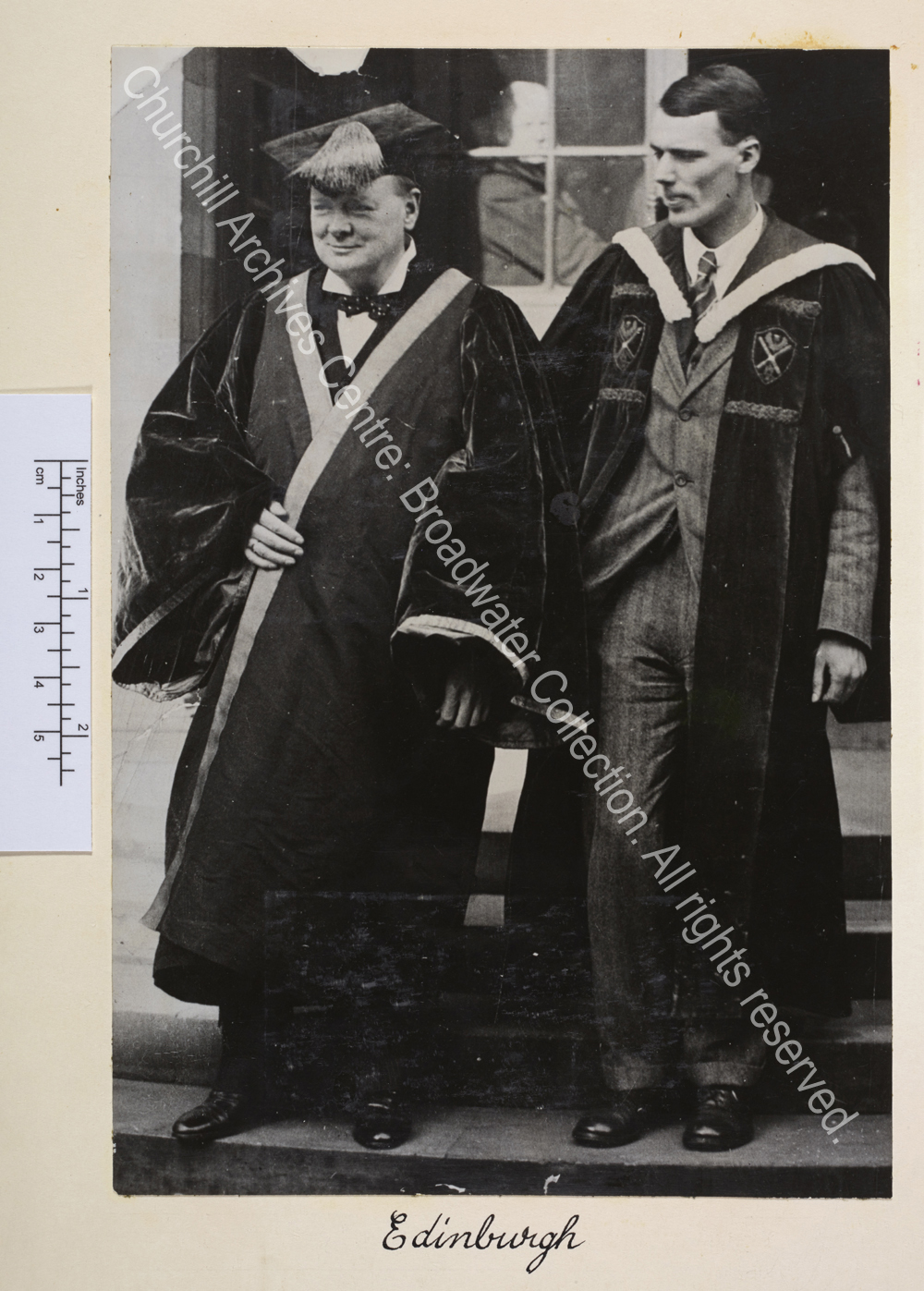 Photo shows WSC wearing academic dress and cap next to a man. Captioned Edinburgh though WSC did not receive an honorary degree from Edinburgh.