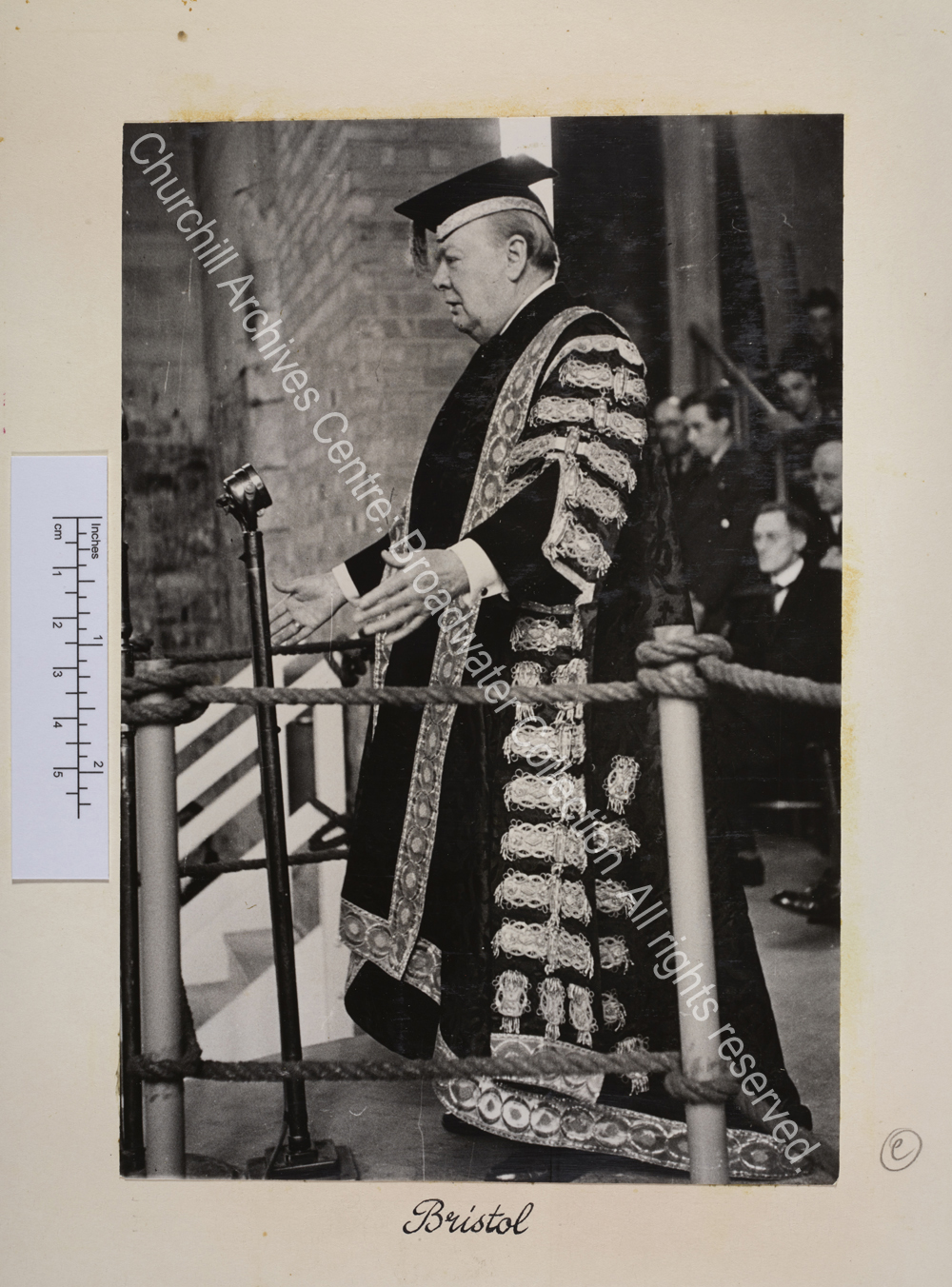 Photograph of WSC wearing his robes as Chancellor of Bristol University speaking at a microphone.