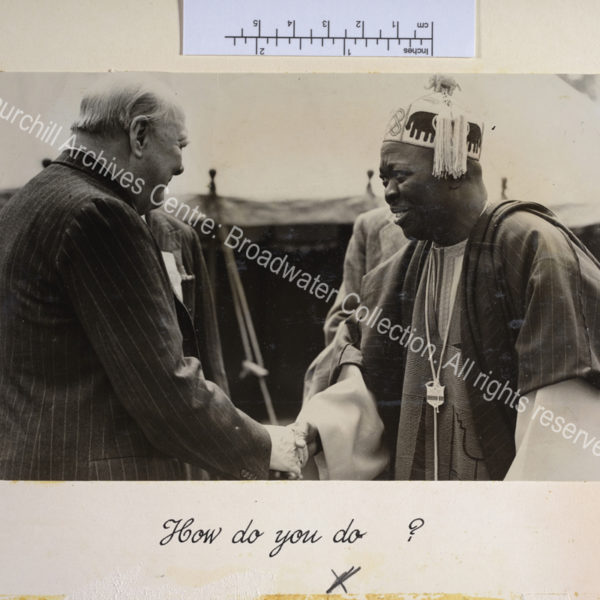 Photo shows WSC shaking hands with the Oni of Ife. The Oni of Ife is wearing traditional dress and a members' badge for the Kent County Agricultural Show.