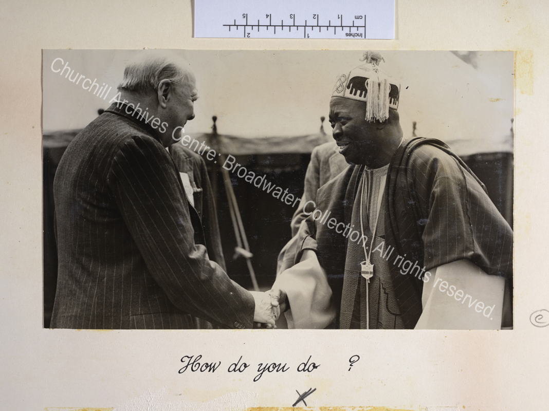 Photo shows WSC shaking hands with the Oni of Ife. The Oni of Ife is wearing traditional dress and a members' badge for the Kent County Agricultural Show.