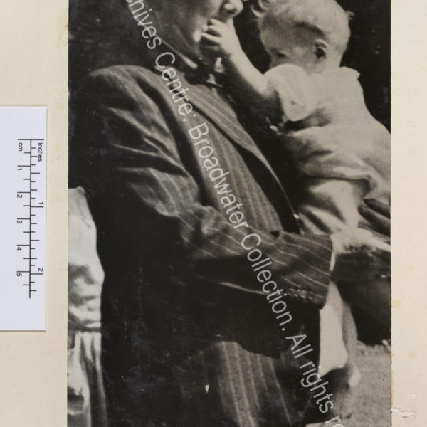 Photo shows WSC holding a baby in his arms. The baby is putting her hand in his mouth.