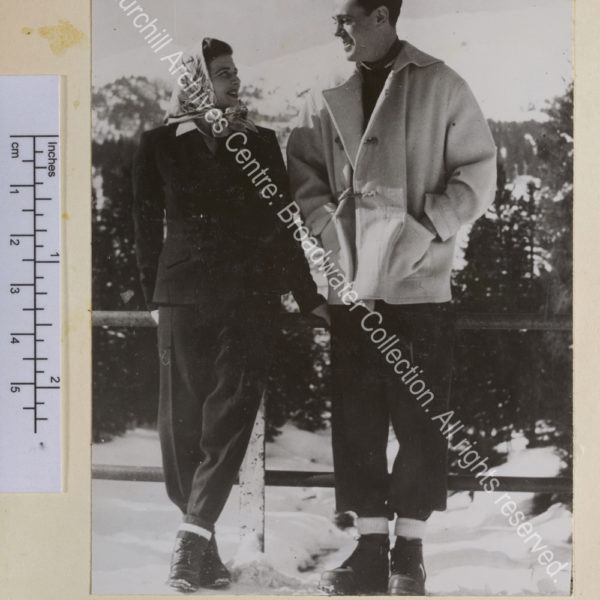 Photo of Mary Soames [earlier Mary Churchill] and Christopher Soames [?on their honeymoon in Switzerland] smiling at each other. They are wearing winter clothing and walking boots and in the background is a snow covered mountain.