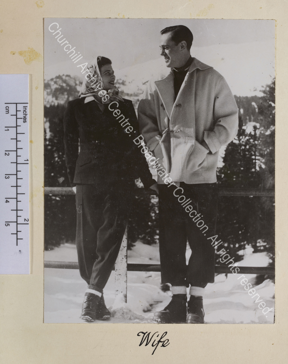 Photo of Mary Soames [earlier Mary Churchill] and Christopher Soames [?on their honeymoon in Switzerland] smiling at each other. They are wearing winter clothing and walking boots and in the background is a snow covered mountain.