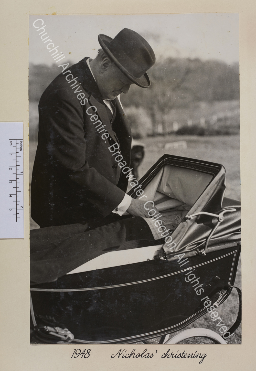 Photo shows WSC smiling at Nicholas [Soames] who is a baby in a pram. WSC reaches in to stroke Nicholas' cheek.