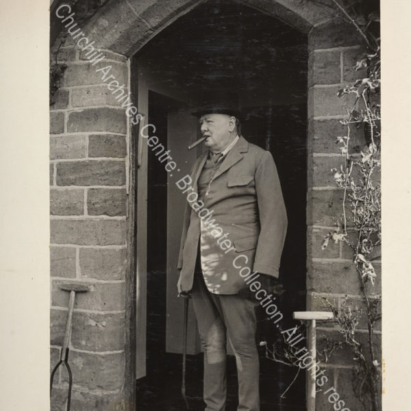 Photo shows WSC standing in a doorway wearing riding clothes and carrying a riding crop. [The occasion was WSC joining the Surrey and Burstow hunt to celebrate his 74th birthday].