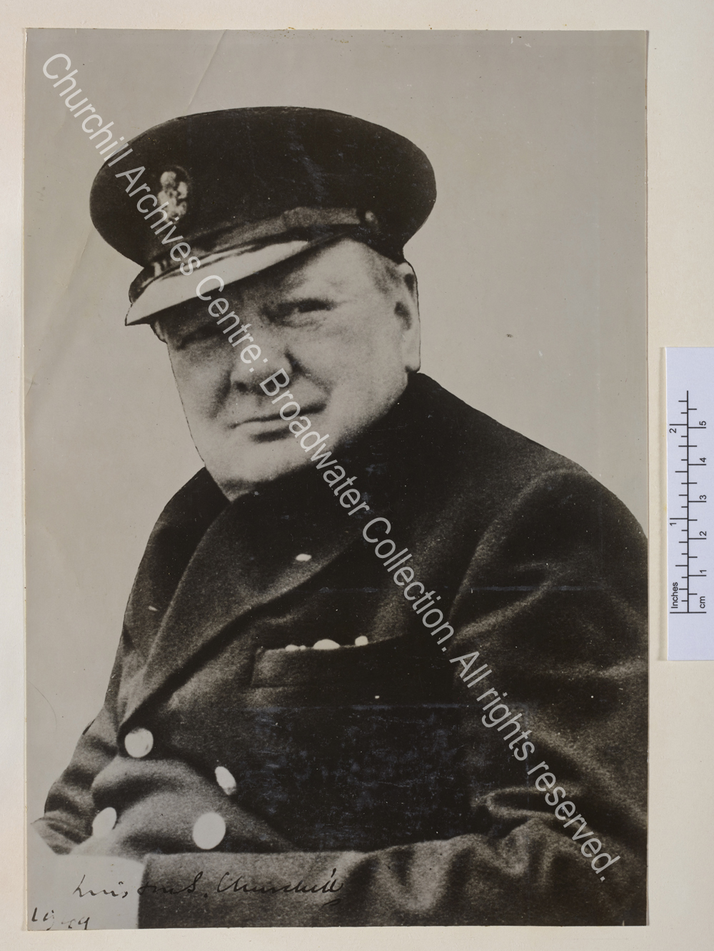 Head and shoulders photo of WSC wearing a peaked cap. Signed "Winston Churchill 1949".