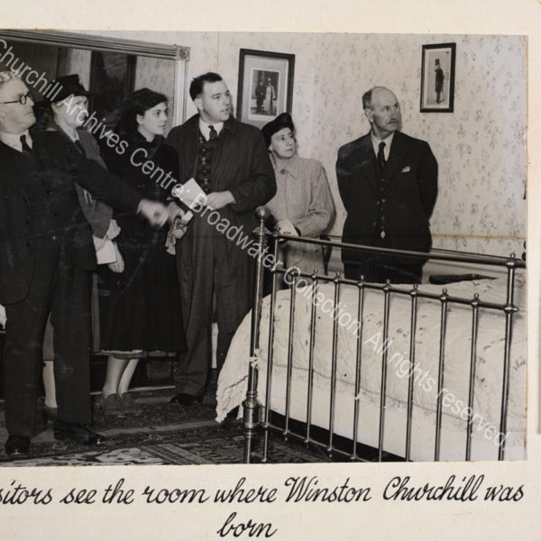 Photo shows members of the public standing in the bedroom [at Blenheim Palace] where WSC was born.