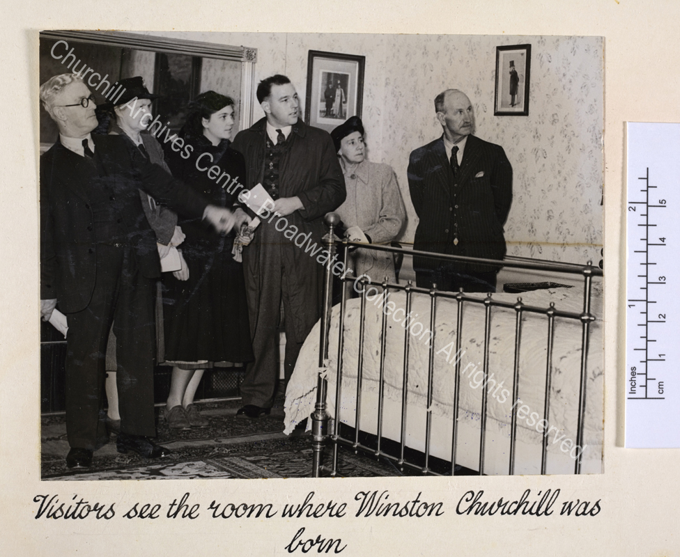 Photo shows members of the public standing in the bedroom [at Blenheim Palace] where WSC was born.