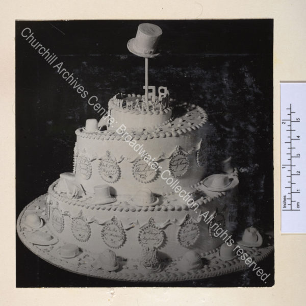 Three-tiered birthday cake decorated with different styles of hat worn by WSC.