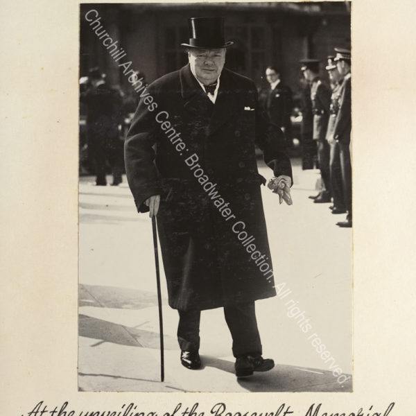 Photo shows WSC walking towards the camera. He is wearing an overcoat and top hat
