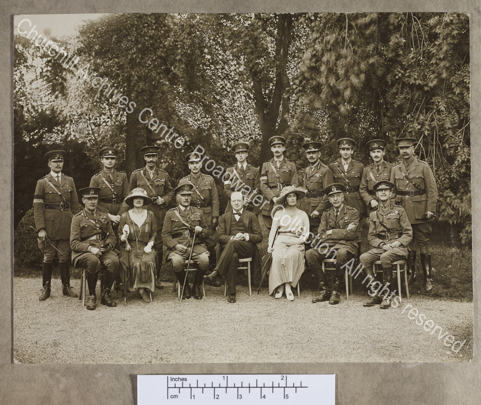 Photograph of WSC [? Secretary of State for War] with various officers and two ladies including CSC in one seated row