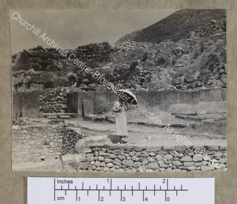 Photograph of CSC [while on a cruise of the Eastern Mediterranean on 1st Lord Moyne's yacht the Rosaura].  She is standing in the middle distance amid the walls of a ruined [?] classical site