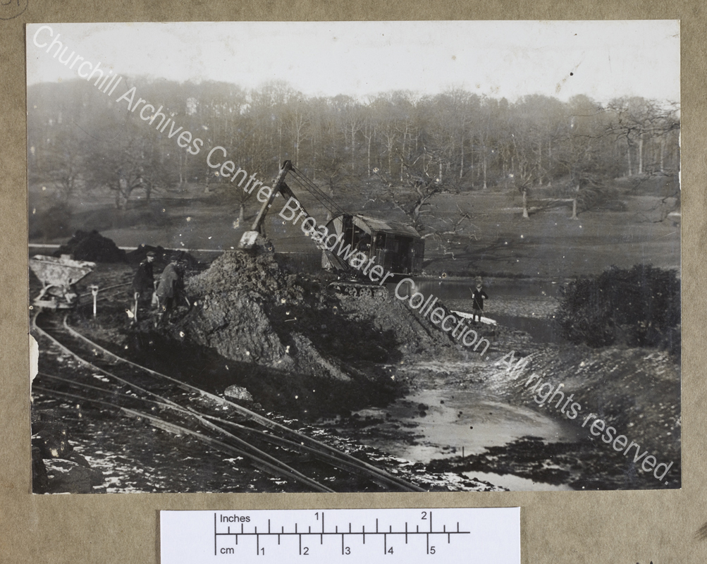 Photograph of a mechanical excavator and workmen digging in the drained lower lake at Chartwell [Kent]